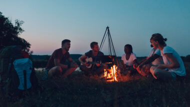 A group of friends sitting around the campfire during their camping trip.