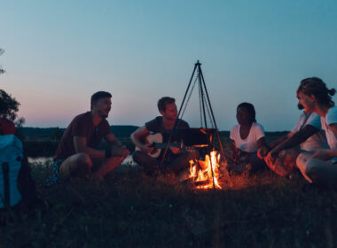 A group of friends sitting around the campfire during their camping trip.