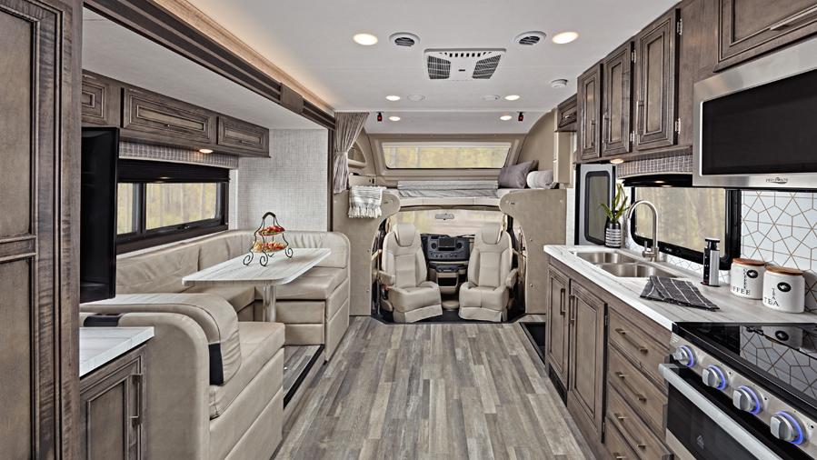 Interior shot of the Entegra Odyssey Class C RV, one of the best small RVs. It shows brown cabinets, a u-shaped dinette, the driving area, and the cab over space. 