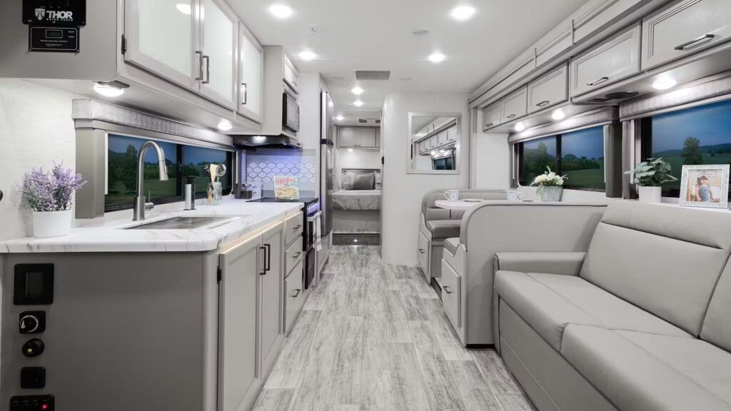 Interior shot of the Thor Chateau, one of the best small RVs. Showing white interiors, light cabinet and couch colors and bright lights.
