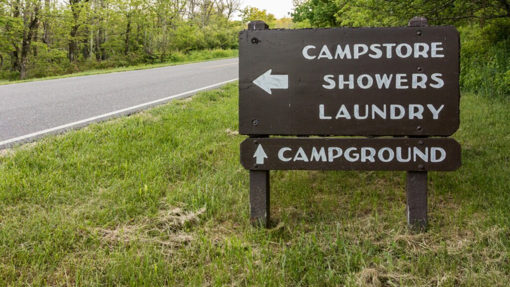 A sign by a road pointing to a camp store, showers, laundry and campground.