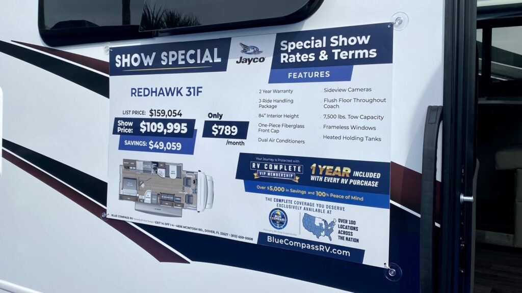 A banner taped to the side of the RV showing the show price and features. 