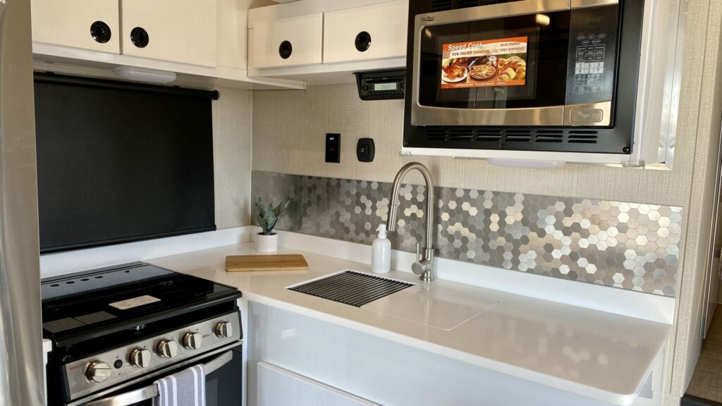 kitchen sink fixture in an RV with white counters and a silver backsplash