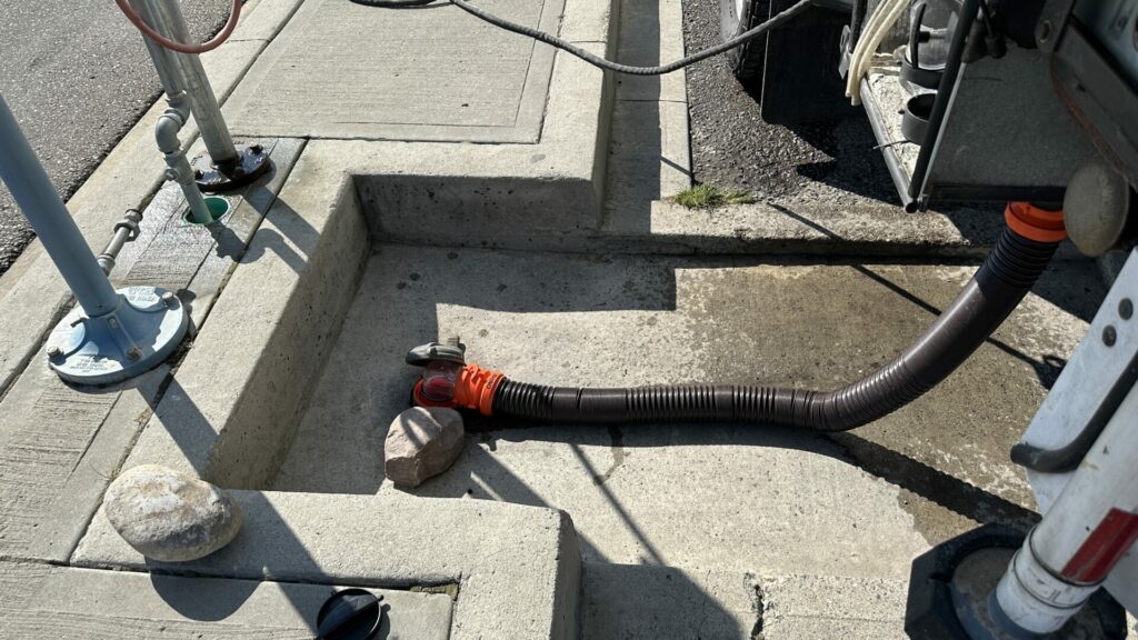 RV sewer hose hooked up to dump station dumping waste tanks