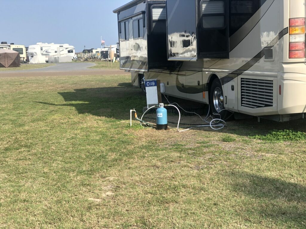 RV hooked up to campground water faucet with hose