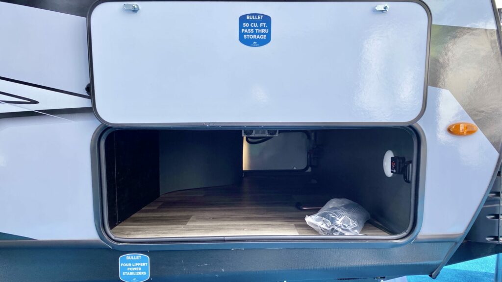 The outside of a travel trailer with the storage compartment open, showing how much space is available. It's important to consider storage space when looking at RV floor plans. 