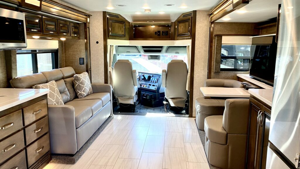Interior of a Class A motorhome showing the driving area, couch, dinette, and some of the kitchen.