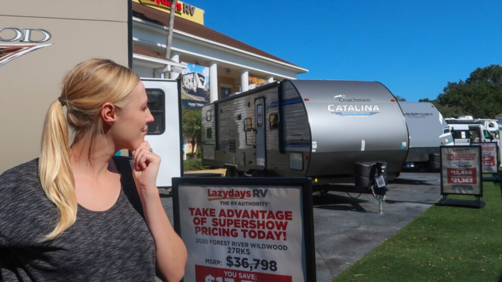 A woman at the Lazydays RV dealership looking at a row of RVs contemplating which one to go into.