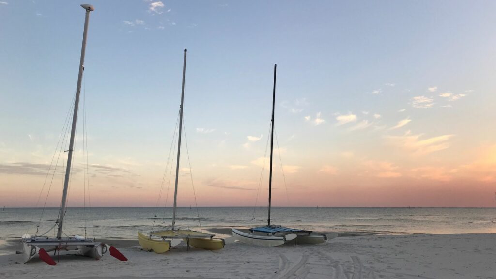 A peaceful beach with 3 small sail boats on the sand in gulf shores, alabama