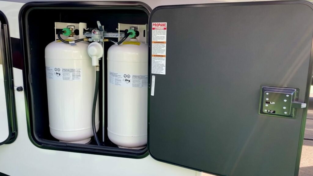Two propane tanks inside a bay of an RV with the door open.