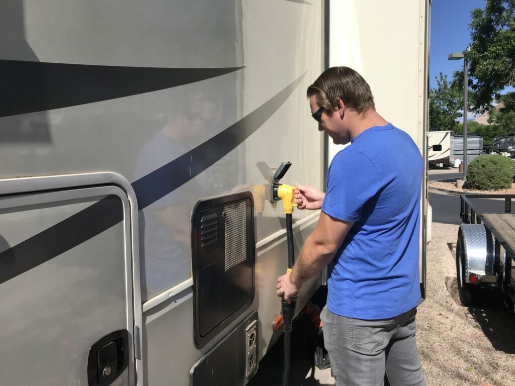 Jason plugging in a extension cord to his RV electrical cable to make sure it reaches
