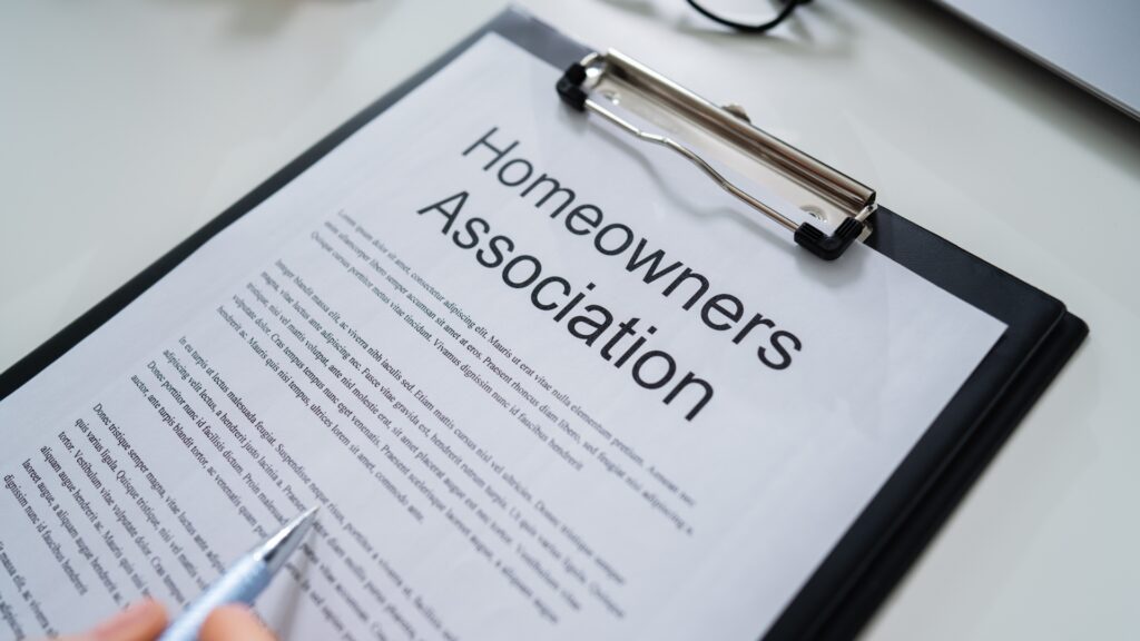 A piece of paper on a clipboard that says "Homeowners Association"  with a pen.