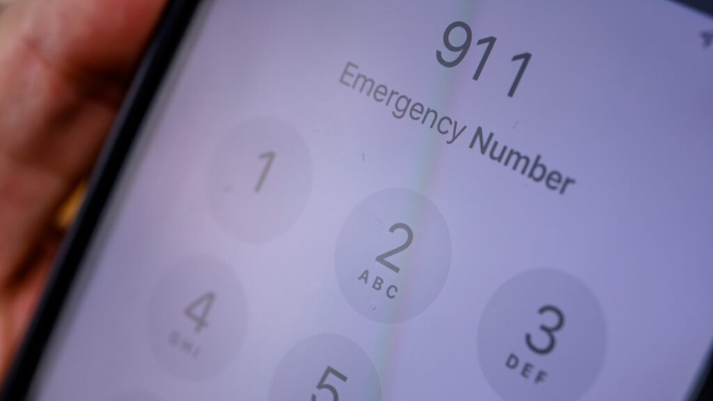 A close up shot of a cell phone showing 911 dialed on the screen.