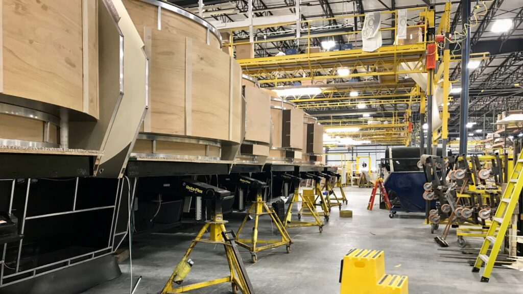 Inside an RV factory with rows of unfinished RVs. 
