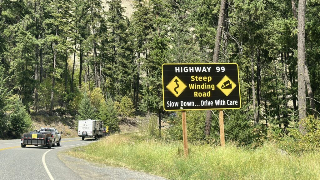 A sign on the sea to sky highway that warns drivers about the steep winding road. 