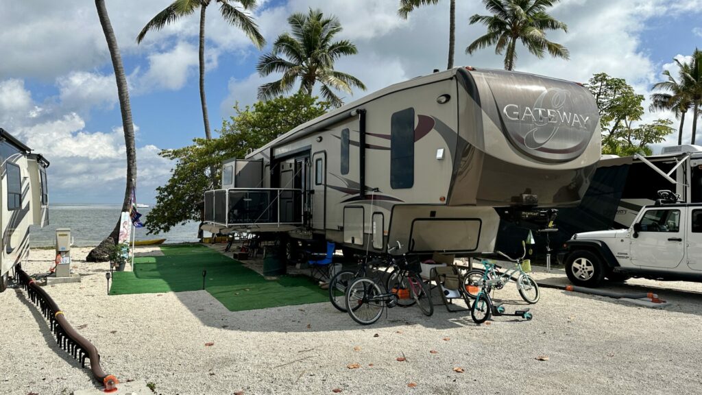 A fifth wheel parked in an RV site that overlooks the ocean. 
