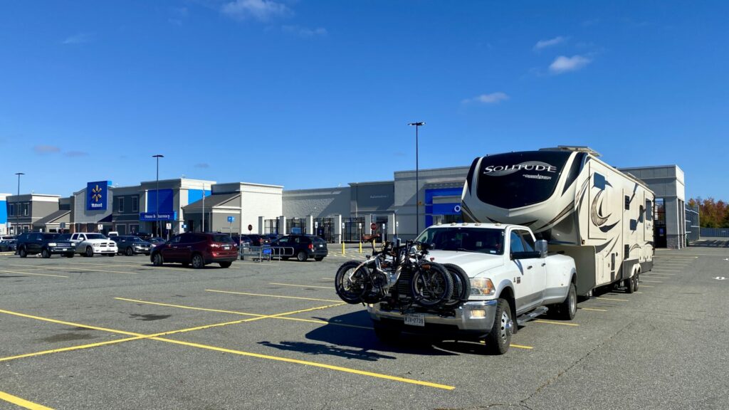 A truck towing an RV parked in a Walmart parking lot.