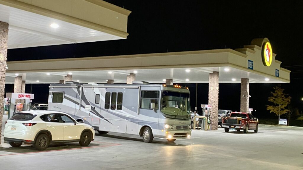 A Class A RV pulling into a gas station to fill up.