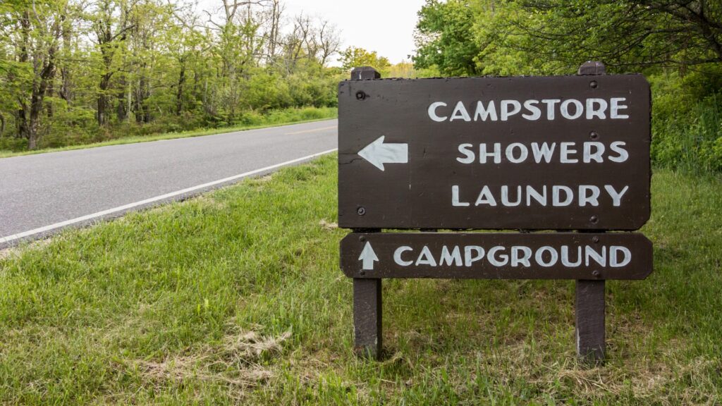 A sign in a campground that points to where the campstore, showers, and laundry are. 