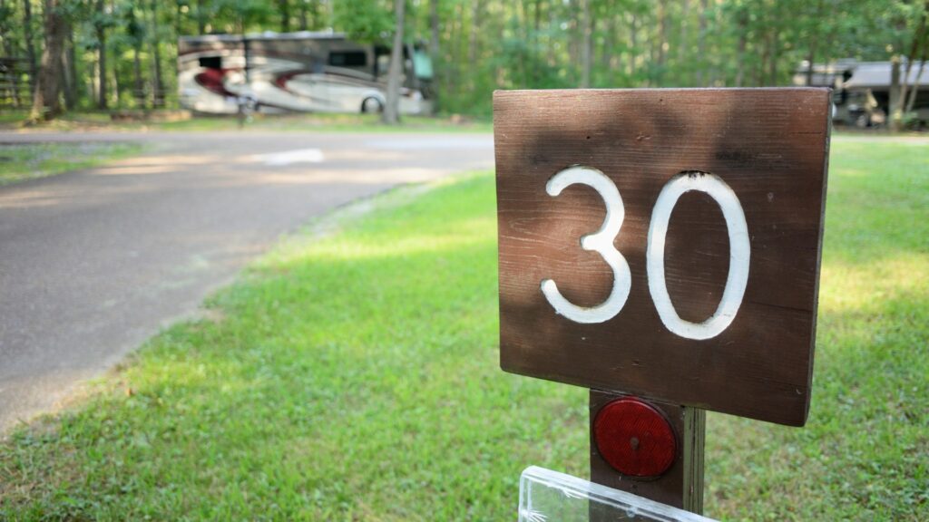 A campsite sign that shows the number 30 with RVs parked in the background.