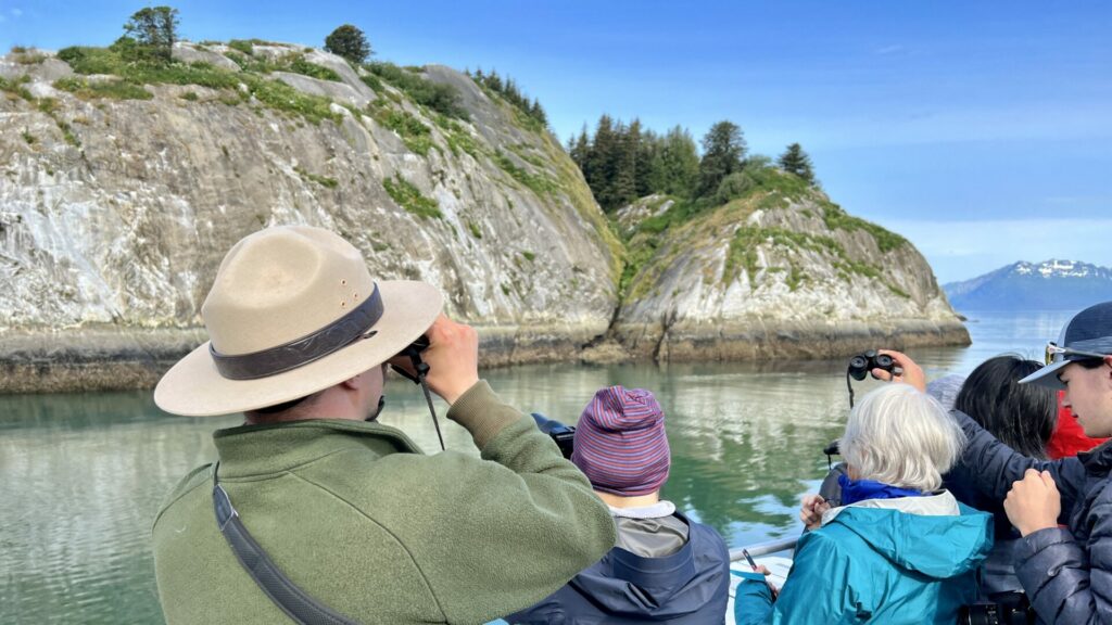 A National Park Ranger looking through binoculars to find wildlife to point out to the tour.