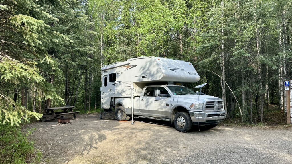 A white truck and truck camper parked in the dry camping area at chena hot springs. 