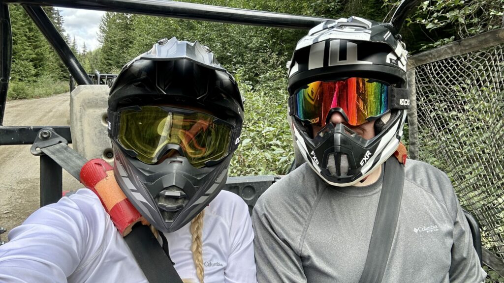 Rae and Jason wearing helmets sitting in a side by side ready to take off on the tour of the mountains in Whistler Canada. 