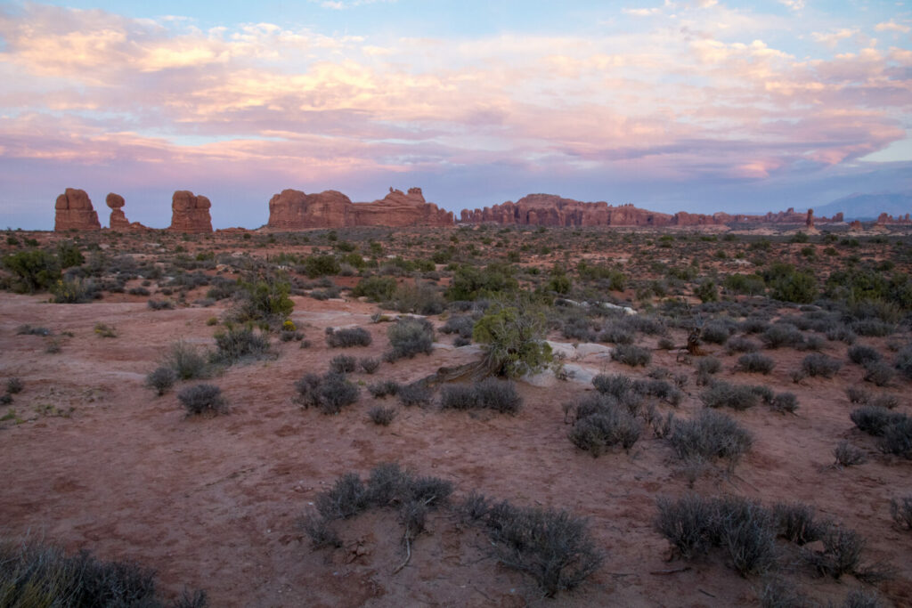 Arches National Park from a distance at sunset, with a purple sky.