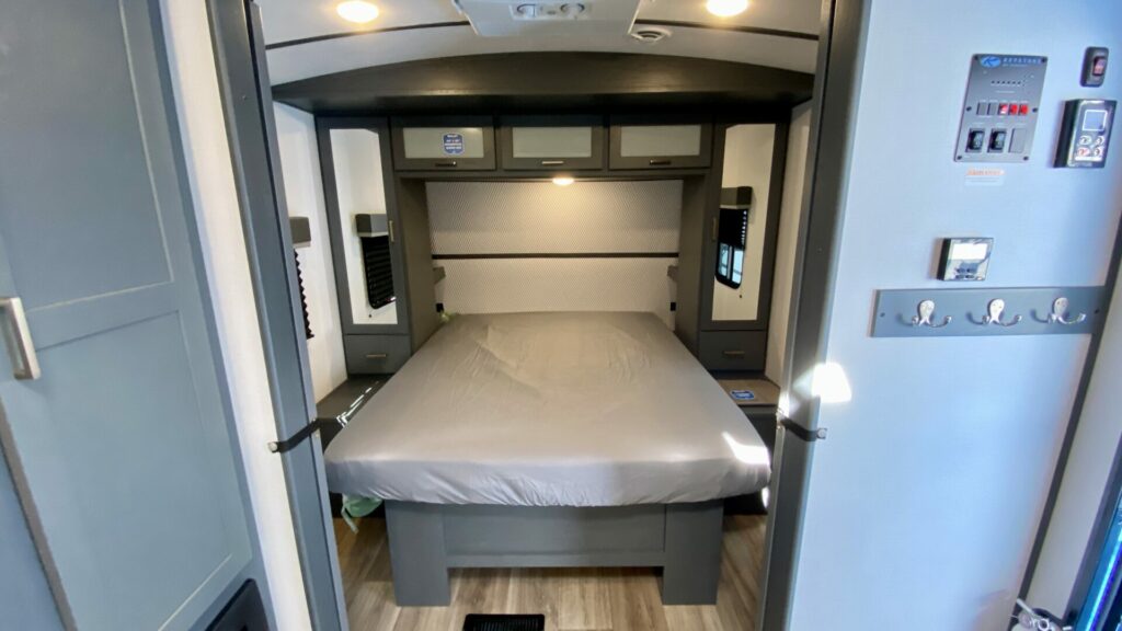 An RV mattress in a travel trailer with only a sheet on it.