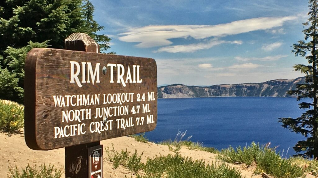 Rim Trail sign with Crater Lake in the background.