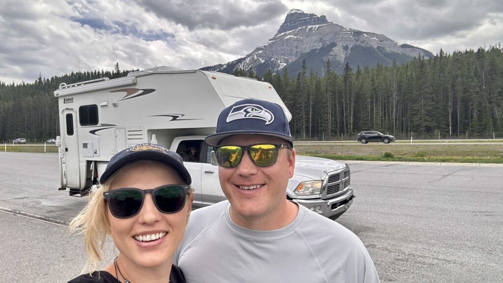 Us standing in front of our truck camper in Canada smiling. 