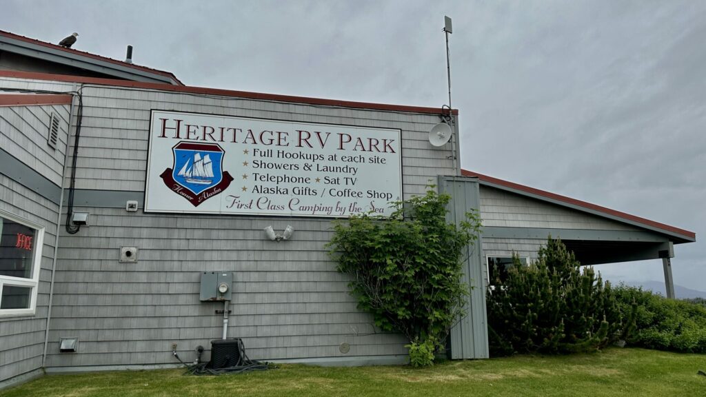 The office building for Heritage RV Park in Alaska with a large sign on the outside that lists their amenities. 