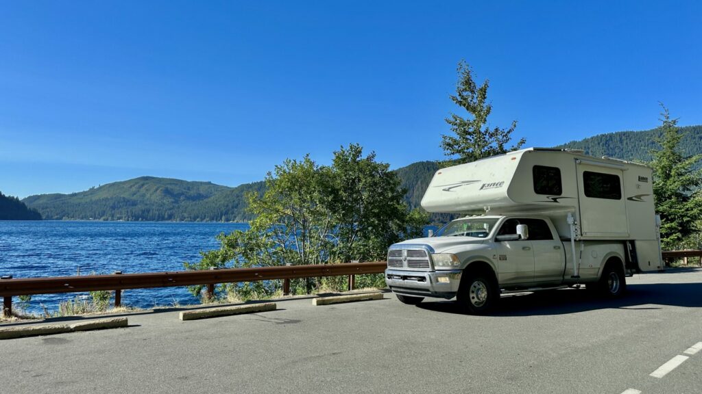 A truck camper parked on the side of the road overlooking Lake Crescent in Olympic National Park. 