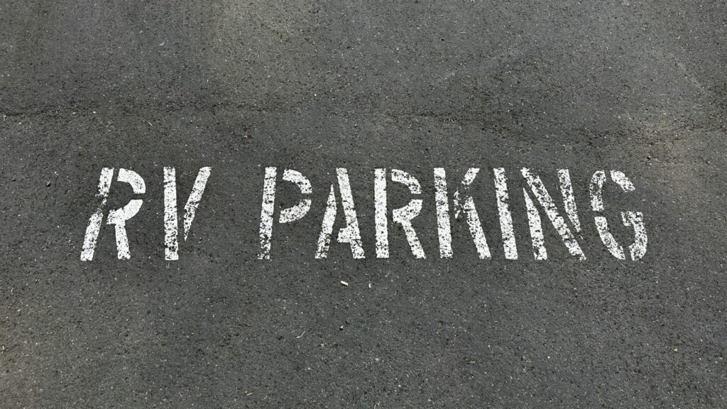 A picture of the words RV PARKING painted on pavement. 