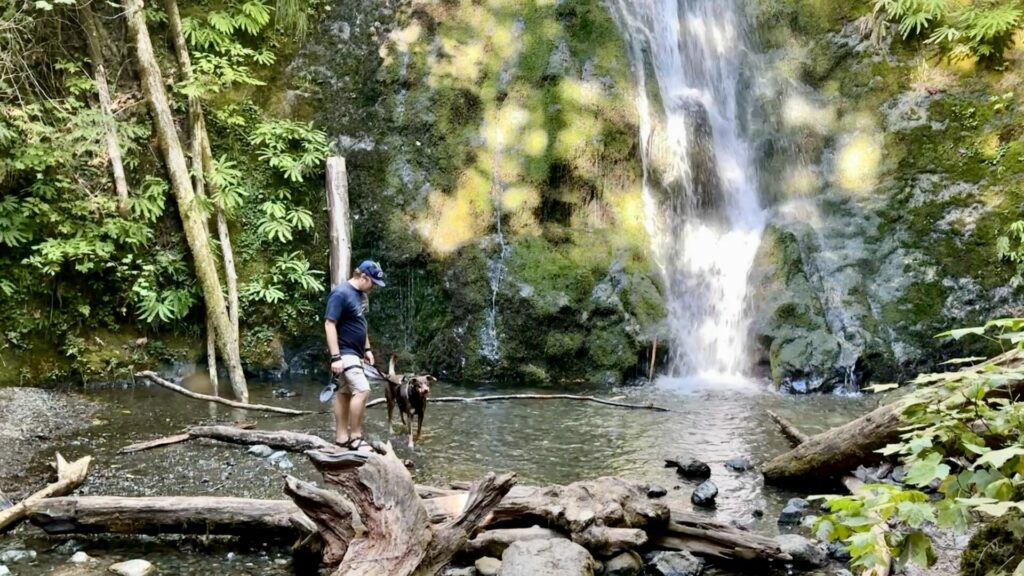 Jason and our dog standing at the foot of a waterfall.