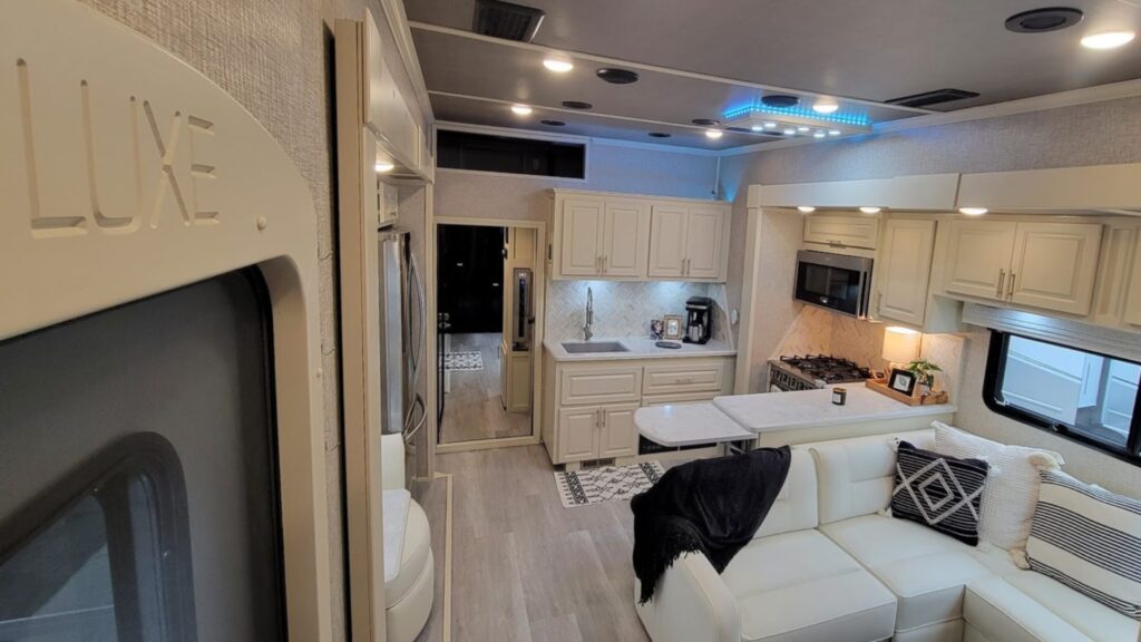 Interior shot of a Luxe toy hauler with white interior and the door to the back patio section on the left.