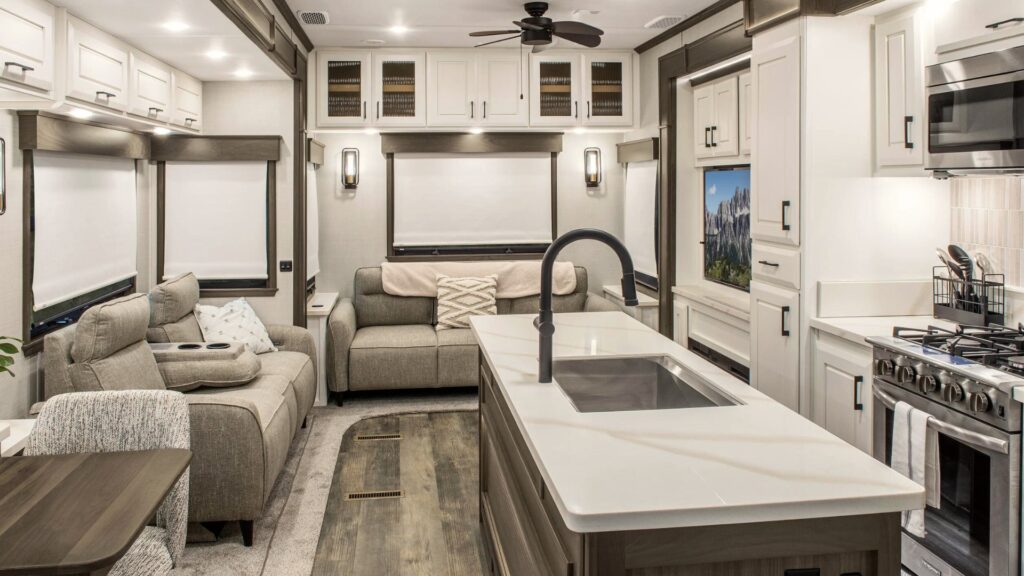 The interior of a DRV Mobile Suites showing the white cupboards, linen couches, and stainless steel appliances.