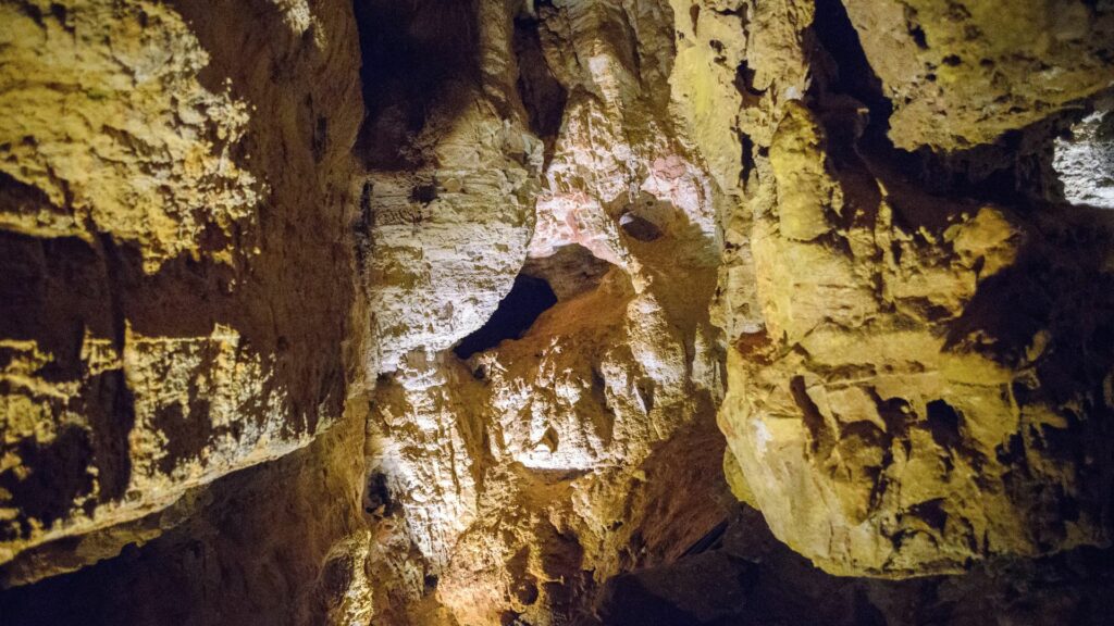 Inside a cave with natural rock formations light up by artificial light.