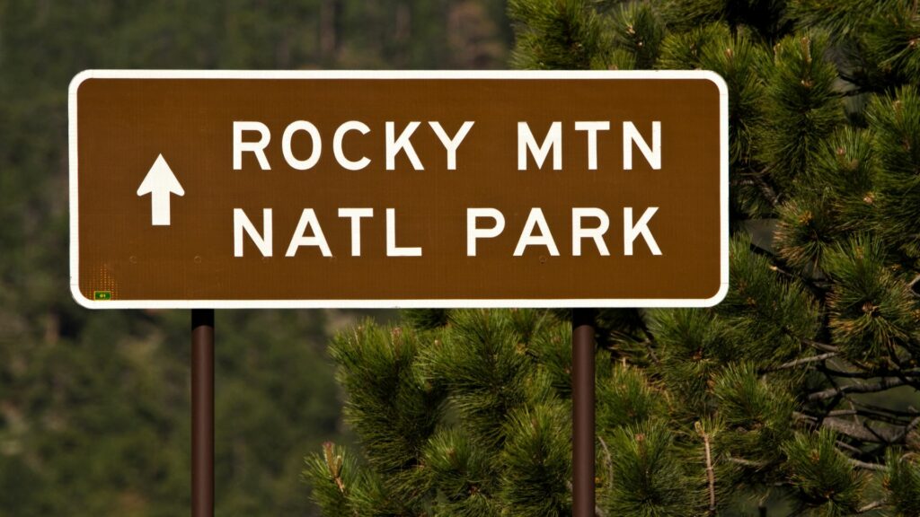 A sign that has an arrow pointing straight and says "Rocky Mtn Natl Park".