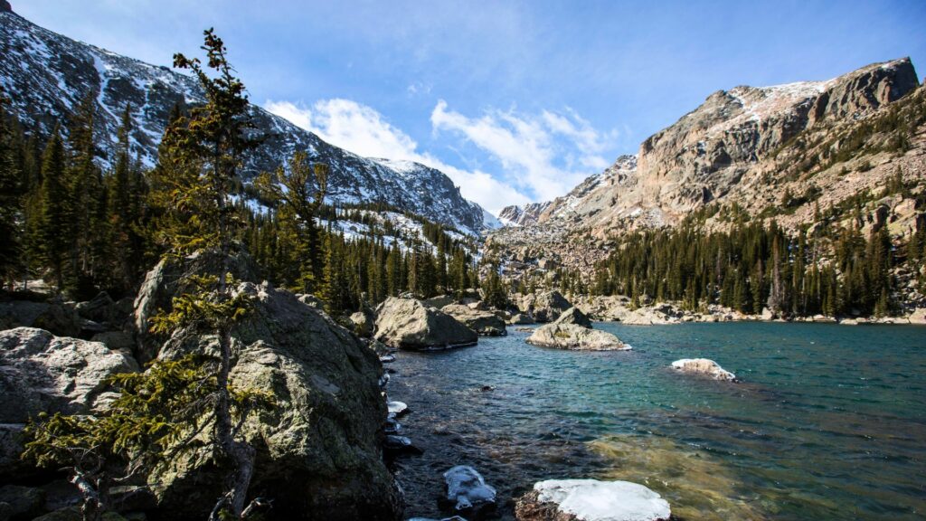 A beautiful lake in Rocky Mountain National Park with some snow still on the rocks surrounding it. 