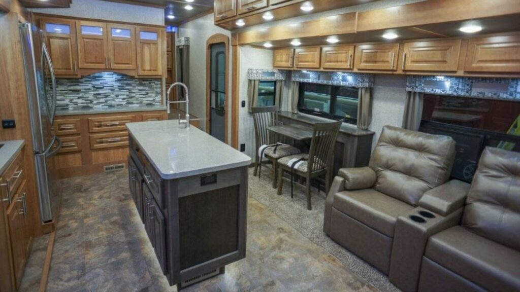 Interior shot of a Luxe fifth wheel with brown couches and cabinets.