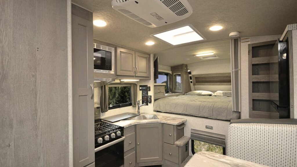 The inside of a northwood manufacturing truck camper with gray interior and one slide out.