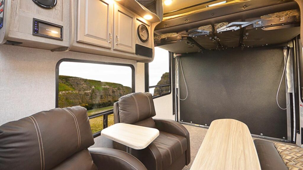 The inside of a northwood manufacturing toy hauler with gray cabinets and brown seats.