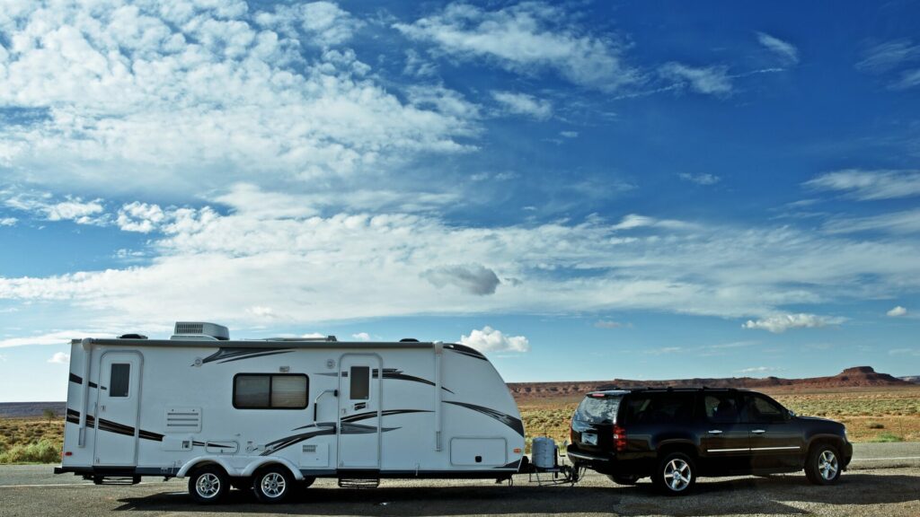 A travel trailer being towed by an SUV parked in the desert.