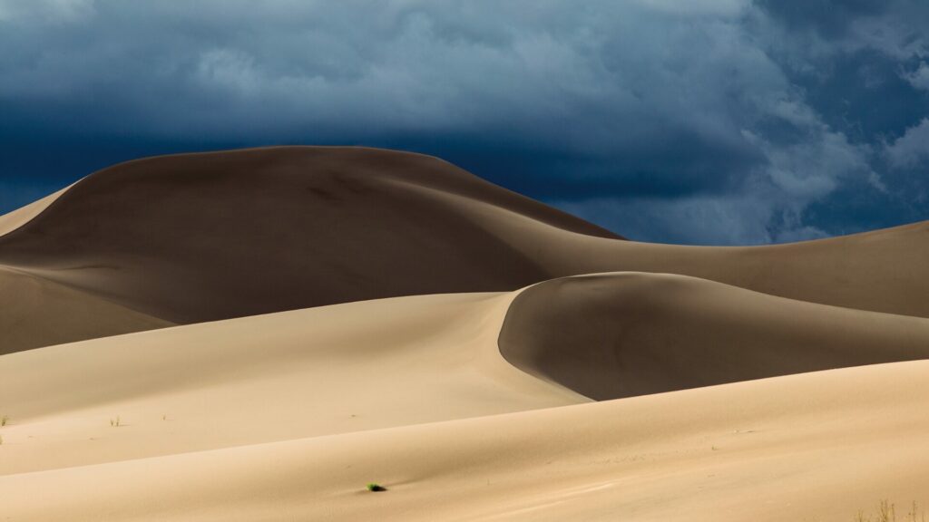 Sand Dunes National Park dunes with a darky cloudy sky in the background.