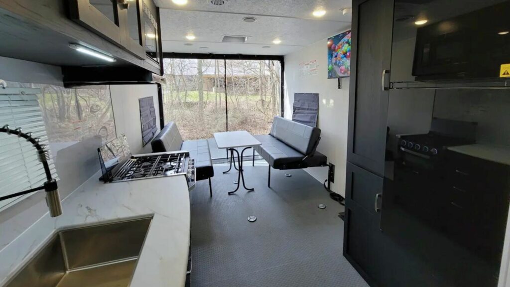 The interior of the 23LT model of Work and Play. Showing black cupboards, white counters, and the table where you can also store toys.