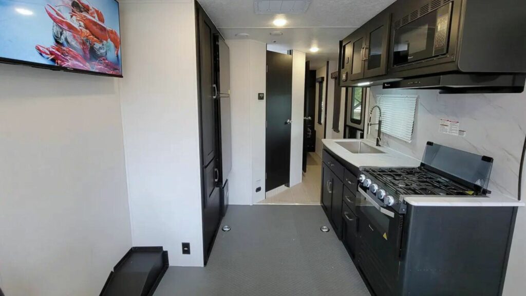 Interior of a work and play toy hauler showing the kitchen leading into the back bedroom. 