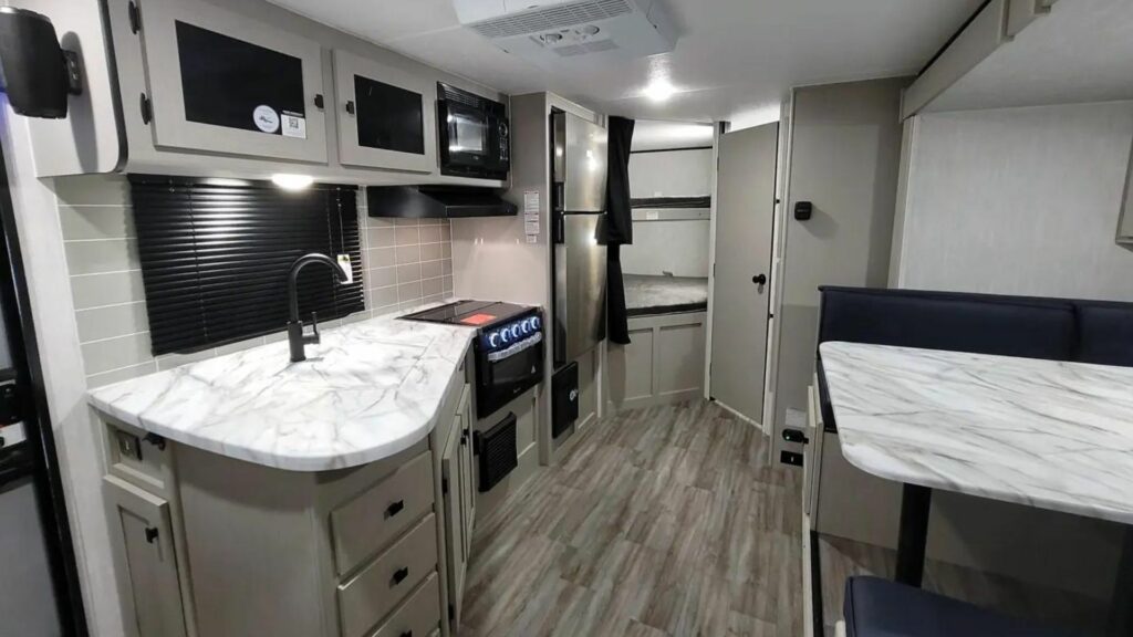 The inside of a Coachmen Apex with the kitchen in the center of the RV and the bunk beds and bathroom in the rear.