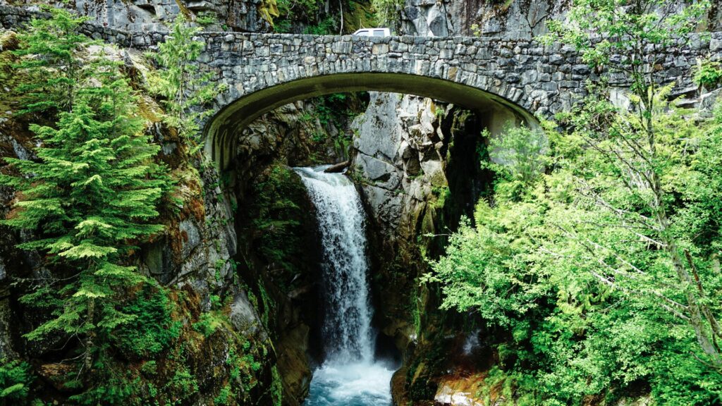 Narada Falls in Mount Rainier National Park with a stone bridge framing the waterfall. 