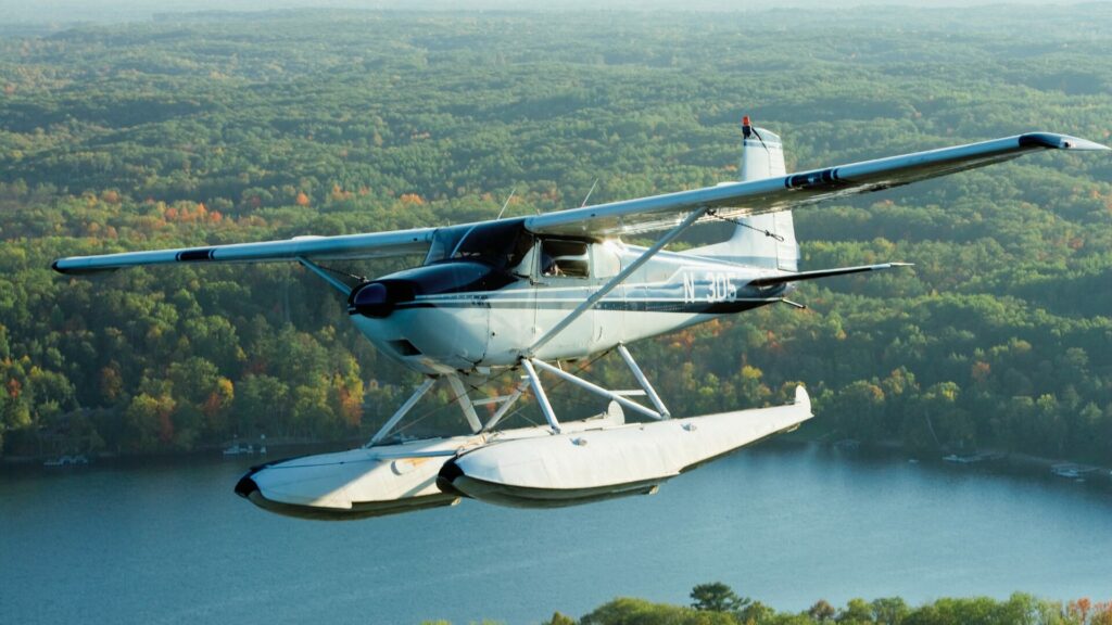 Floatplane flying over a body of water and fall changing foliage. 